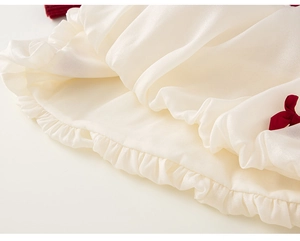 Detail eines Baby Mädchenkleides mit weißem Satin-Rüschensaum und dunkelroter Schleife