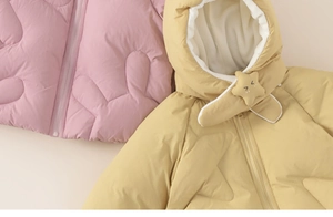 Detail van gewatteerde donsjassen voor kinderen in roze en geel met sterrenkap en fleece