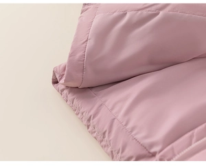 Detailopname van de roze gewatteerde donsjas met stiksels en een matte stoftextuur