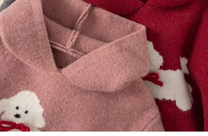 Dettaglio della morbida trama in maglia e jacquard a cucciolo bianco con fiocco rosso