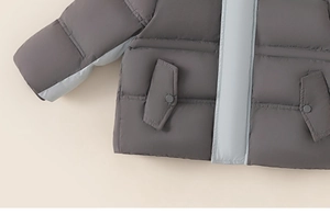 Detailed view of kids down jacket showing quilted stitching and secure snap pocket design