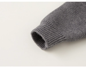 Dettaglio dei polsini a costine su un maglione lavorato a maglia grigio scuro per bambini