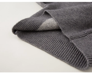 Dettaglio ravvicinato di un maglione grigio scuro con orlo a coste e motivo jacquard