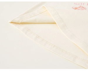 Makro-Detail von Stricksaum mit rosa Self-Schriftzug und süßem Cartoon-Bär-Aufdruck