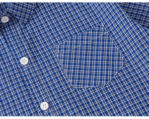 Detailed view of kids' blue plaid shirt fabric with white buttons and front pocket