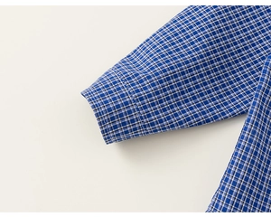 Detail of blue and white plaid cotton shirt cuff showing neat stitching and fine fabric texture