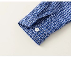 Close-up of blue and white plaid shirt cuff with white button and fine stitching details