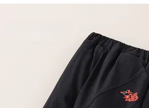 Detail of children's black cotton pants featuring elastic waist and festive cloud prints