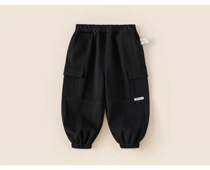 Detail der schwarzen Kinder-Cargohose mit elastischem Bund und seitlicher Tasche mit Etikett