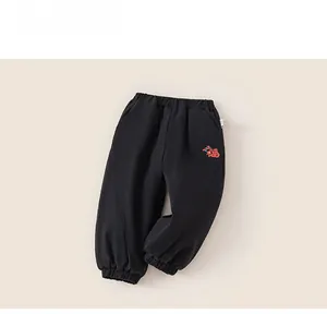 Detail of black cotton kids pants with red Fu character embroidery and elastic waist