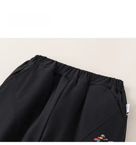 Detail of elastic waistband and colorful pattern on children's black winter cotton trousers