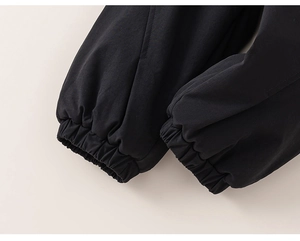Close-up of black children cotton pants featuring elastic ribbed cuffs and woven texture