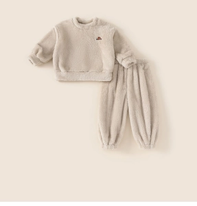 Detail of soft cream fleece kids pajama set featuring a car embroidery on the chest