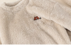 Close-up of soft beige fleece children's sweatshirt with cute brown bear embroidery
