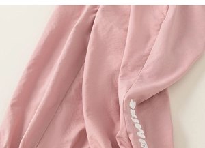 Détail du pantalon rose pour fille avec broderie de lettres blanches et texture plissée douce