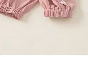 Détail du jogging rose pour filles avec poignets élastiques et broderie cœur blanche
