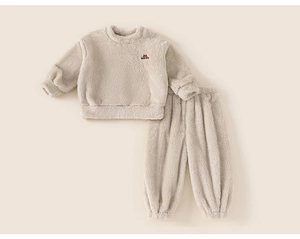Detail view of cream plush fleece children's pajamas with soft texture and ribbed cuffs