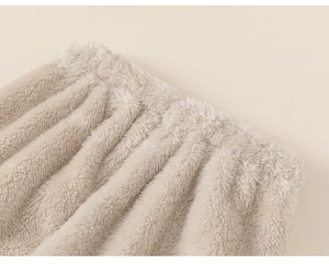 Detailed macro view of the thick beige plush fabric and elastic waistband on baby pajamas