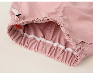 Détail d'une veste rose montrant l'ourlet élastique et les coutures blanches renforcées