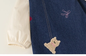 Détail de la robe en jean bleu marine avec broderie ours et chemise blanche