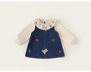 Détail de la broderie ours et du patch cœur sur une robe en denim bleu marine pour fille