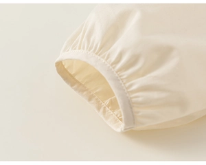 Détail des poignets plissés en coton beige montrant une texture fine et une coupe élégante