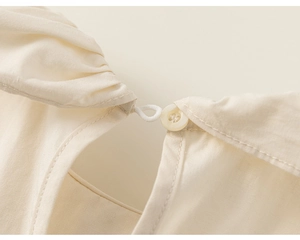 Détail du bouton en résine et de la boucle élastique sur le pantalon en coton pour fille