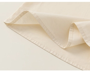 Détail de l'ourlet en coton crème avec une finition de couture précise à double aiguille