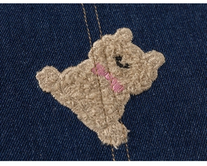 Gros plan détaillé sur la broderie d'ours et les coutures sur le tissu denim foncé