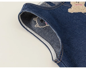 Détail d'un jean bleu foncé avec des motifs mignons de chat et d'ours brodés