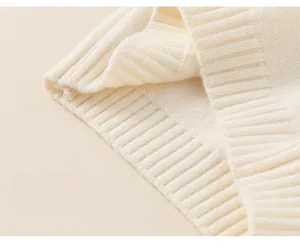 Detailed macro view of the soft ribbed hem on a cozy cream-colored knit sweater for children