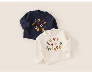 Detail of soft knit texture and colorful embroidered letters on toddler sweaters