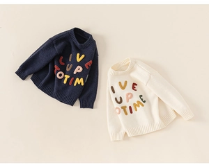 Detail of kids knit sweaters with colorful embroidered letters and ribbed cuffs