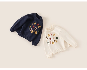 Close-up of navy and cream knit sweaters with colorful 3D embroidery for kids