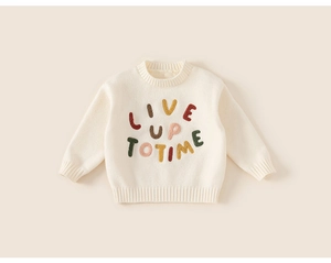 Close-up of cream knit sweater featuring colorful embroidered Live Up To Time text