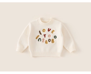 Close-up of the colorful 3D embroidery detail on this beige knit sweater for kids