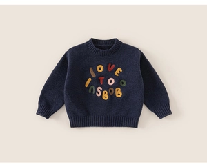 Detail of navy blue kids sweater with colorful embroidered letters and ribbed cuffs