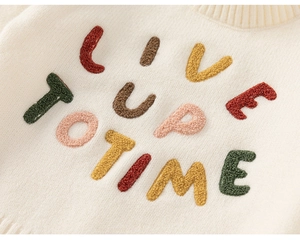 Detail of colorful towel embroidery letters on cream white knit sweater for kids
