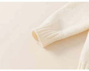 Detailed macro view of the soft cream knit fabric and ribbed cuffs on this cozy sweater