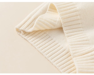 Detailed close-up of ribbed knit texture on a soft cream-colored toddler winter sweater