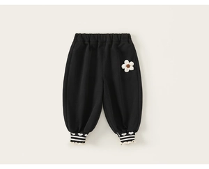 Détail d'un pantalon enfant avec fleur 3D blanche et poignets élastiques rayés noirs
