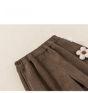 Détail d'un pantalon en velours côtelé marron avec taille élastique et fleur décorative en tissu