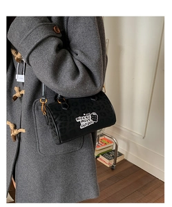 Close-up of black animal print cylindrical bag with cloud embroidery and gold metal hardware