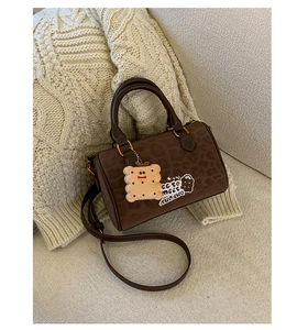 Detailed close-up of brown suede Boston bag with leopard print and cookie plush pendant