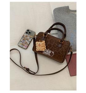 Detailed macro shot of dark brown mini Boston bag with leopard print and cookie embroidery