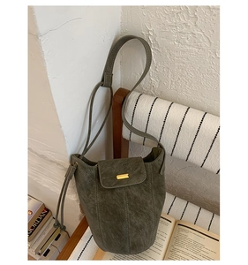 Détail d'un sac seau vintage vert foncé avec ferrures dorées sur une chaise en bois