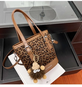 Detalle macro de bolso cubo de leopardo con colgante de peluche y logotipo en la base
