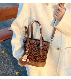Detalle del bolso de cubo con estampado de leopardo y colgante de peluche en una modelo