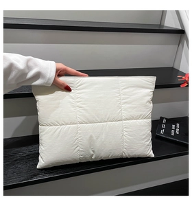 Detail einer weißen gesteppten Nylon-Clutch mit quadratischen Nähten und Reißverschluss