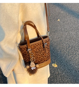 Detalle del bolso de cubo con estampado de leopardo, asas de cuero y hebillas doradas